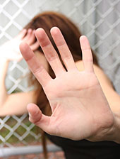 Eine junge Frau macht mit der Hand eine abwehrende Bewegung.