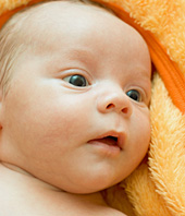 Gesicht eines jungen Babys, angekuschelt an ein Handtuch