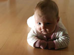 Das Bild zeigt ein Baby, das auf dem Bauch liegt.