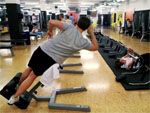Das Bild zeigt einen Mann, der in einem Fitnessstudio Kraft trainiert.