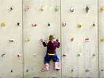 Man sieht ein kleines Mädchen, dass an einer Kletterwand klettert.