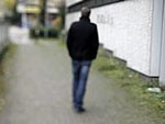 Die Rückansicht eines Mannes, der allein eine Straße runtergeht.
