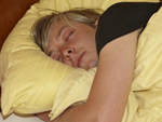 Das Bild zeigt einen jungen Mann, der in gelber Bettwäsche schläft.