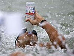 Ein Schwimmer trinkt aus einer Wasserflasche.