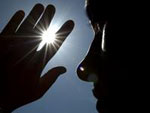 Eine Frau sch�tzt sich mit der Hand vor der Sonne.