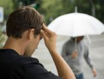 Man sieht einen Mann mit Kopfschmerzen bei Regenwetter.