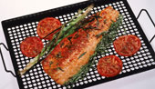 Man sieht gebratenen Fisch mit Tomaten auf einem Rost.