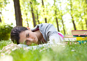 Eine junge Frau liegt m�de auf einer Wiese, neben ihr liegen ein paar B�cher.