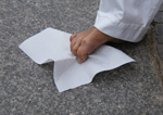 Dieses Bild zeigt einen nackten Fu�, der ein Blatt Papier mit den Zehen vom Boden aufhebt.