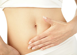 Eine Frau hat eine Hand auf ihren Bauch gelegt.