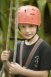 Ein Junge mit Helm und Klettergurt.