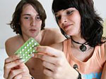 Ein junges P�rchen im Bett, die Frau h�lt einen Tablettenblister in der Hand.