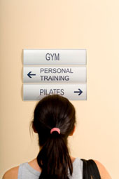 Eine Frau, die vor einem Wegweiser steht: Rechts geht es zum Pilates-Angebot.