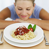 Eine Frau betrachtet mit Vorfreude einen Teller mit Spaghetti Bolognese.
