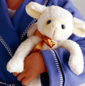 Ein kleines Kind h�lt ein Stoff-Schaf in den H�nden.
