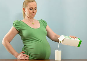 Eine Schwangere gie�t sich ein Glas Milch ein