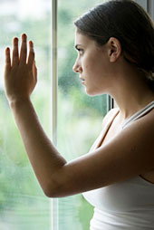 Eine Frau schaut �ngstlich aus dem Fenster.