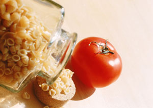 Das Bild zeigt Nudeln und eine Tomate.