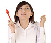 Eine Asiatin h�lt einen L�ffel in der Hand, blickt nach oben und macht einen genie�erischen Ausdruck.