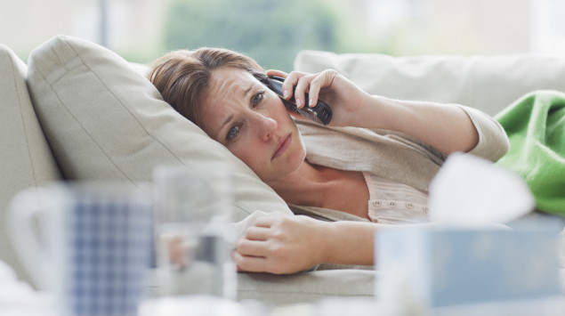 Eine Frau liegt krank auf dem Sofa und telefoniert. Eine Corona-Infektion kann sehr unterschiedlich verlaufen – von sehr mild bis sehr schwer.