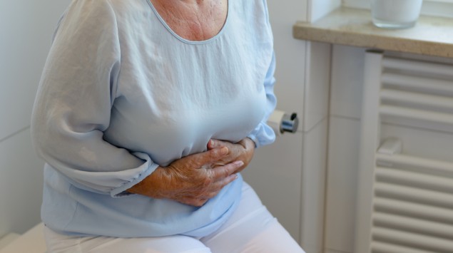 Eine ältere Frau hält sich den Bauch, weil die Divertikel im Darm Beschwerden bereiten.