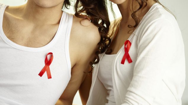 Man sieht einen jungen Mann und eine junge Frau mit einer Aids-Schleife am Shirt.