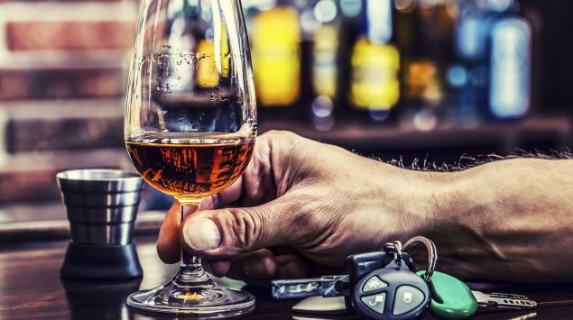 Das Bild zeigt ein Glas Brandy und einen Autoschlüssel auf einer Bar.