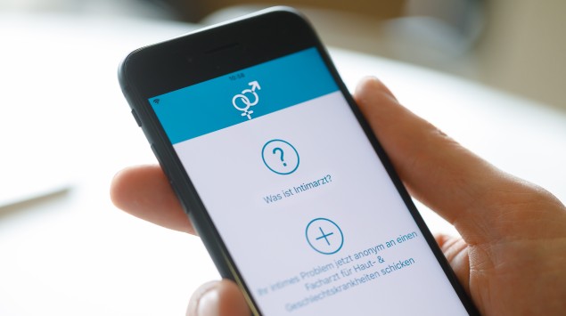 Hand hält Smartphone mit Intimarzt App