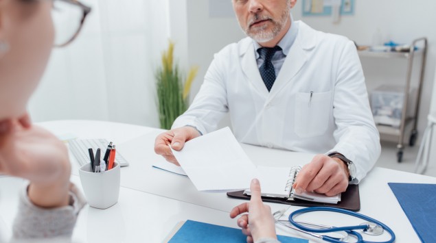 Ein Arzt und eine Patientin am Schreibtisch.