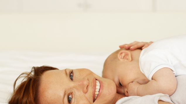 Das Bild zeigt eine Mutter, die ihr neugeborenes Baby im Arm hält.