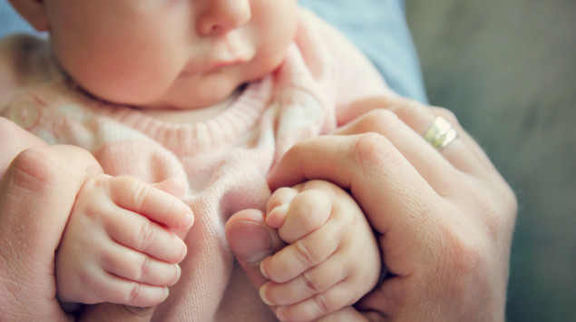 Gelbsucht? Jemand umfasst die Hände eines Babys.