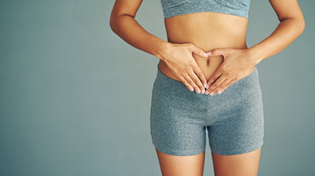 Eine Frau hat die Hände auf ihren Bauch gelegt.