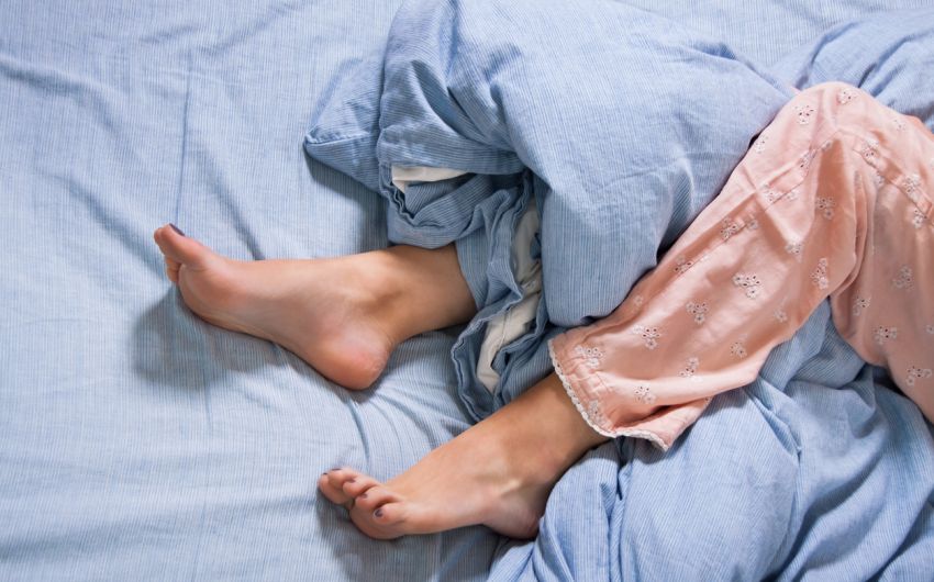 Restless-Legs-Syndrom: Man sieht die Beine einer Frau im Bett.