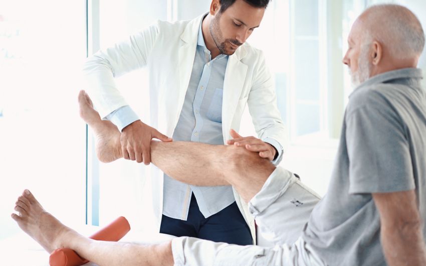 Beinschmerzen: Ein Arzt untersucht das Bein eines Mannes.