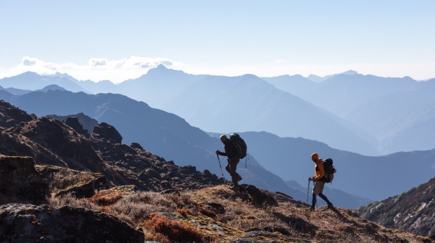 Zwei Personen wandern einen Berg hinauf.