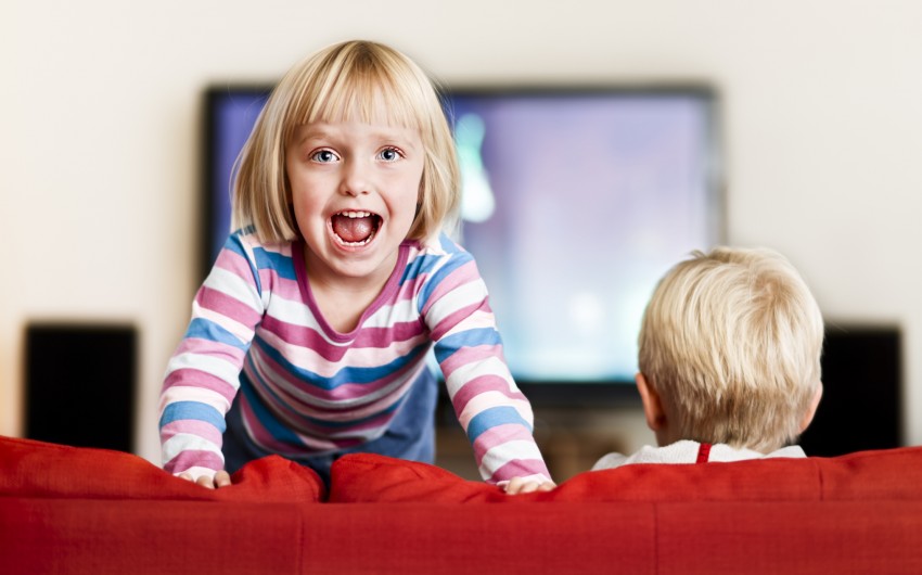 ADHS-Kind tobt auf der Couch vor dem Fernseher
