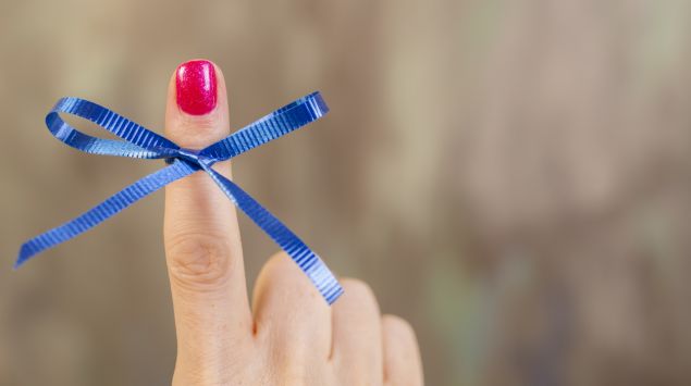 Jemand hat eine blaue Schleife um den Finger gebunden.