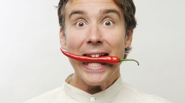 Ein Mann hat eine Chilischote im Mund