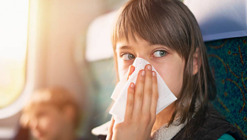 Ein Mädchen in der Bahn putzt sich die Nase. Wegen des Coronavirus sollte man öffentliche Verkehrsmittel derzeit nicht benutzen.