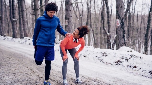 Zwei Jogger machen Dehnübungen.