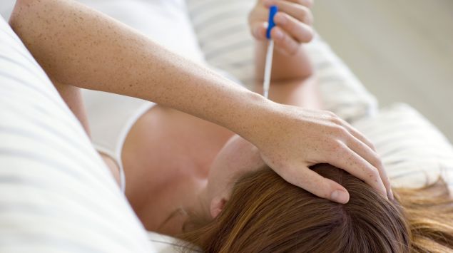 Man sieht eine Frau mit einem Fieberthermometer.