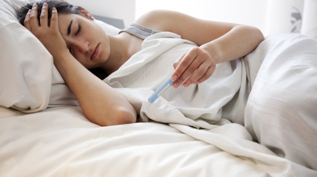 Frau mit Fieber im Bett.
