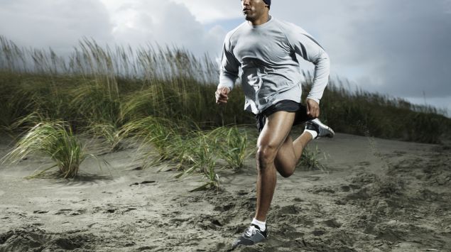 Das Bild zeigt einen sportlichen Mann, der durch den Sand läuft.