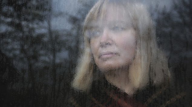 Eine Frau schaut traurig aus dem Fenster.