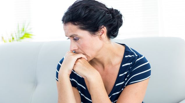 Eine Frau sitzt auf dem Sofa und denkt nach.