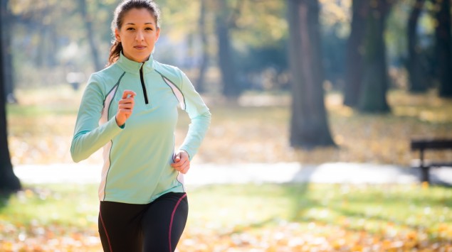 Man sieht eine Frau, die in einem Park joggt.