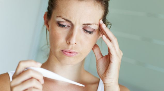 Eine Frau schaut prüfend auf das Fieberthermometer: Menschen mit Hypochondrie befürchten, ernsthaft krank zu sein.