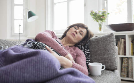 Washilft gegen Durchfall? Eine Frau liegt auf dem Sofa und hält sich den Bauch.