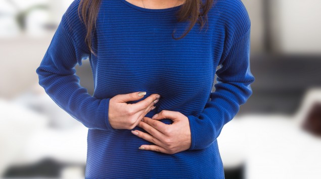 Beschwerden durch Helibacter pylori? Eine junge Frau fasst sich an die Magengegend.