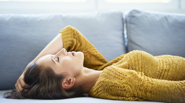 Eine müde Frau liegt auf dem Sofa.